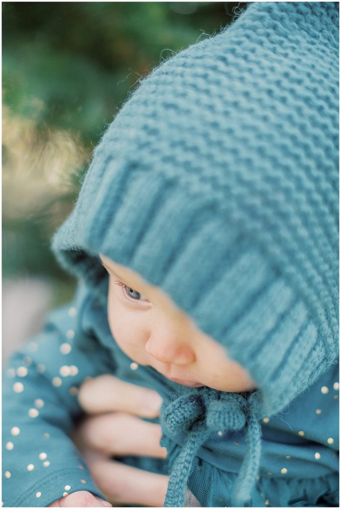 Infant girl in green knit bonnet and outfit.