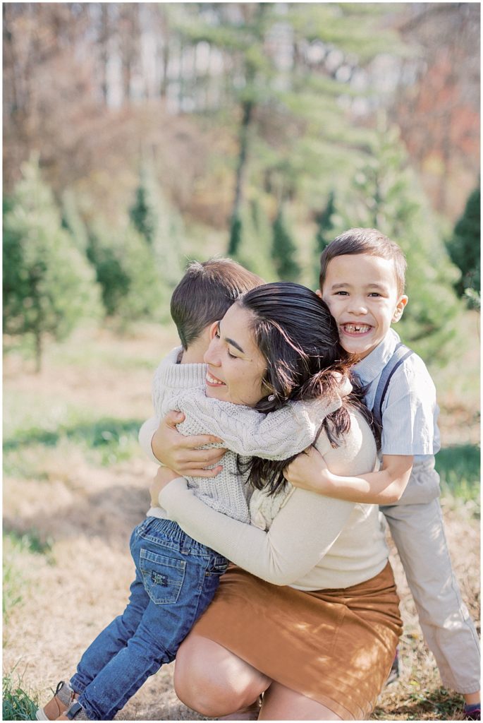 Two sons hug their mother during Christmas mini sessions at Butler's Orchard.