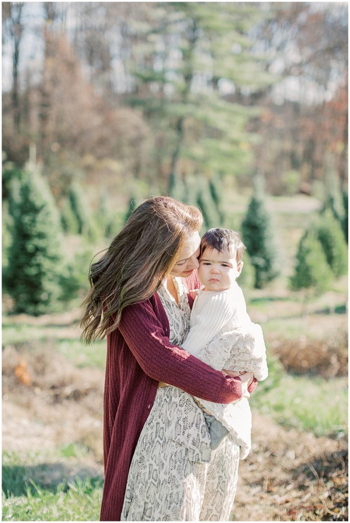 Mother leans into her infant son during Christmas mini sessions at Butler's Orchard.