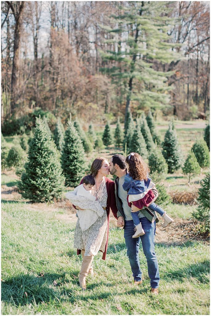 Two parents kiss during Christmas mini sessions at Butler's Orchard