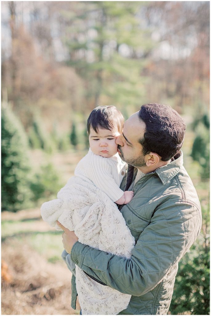 Father kisses his son's cheek during Christmas mini sessions at Butler's Orchard.