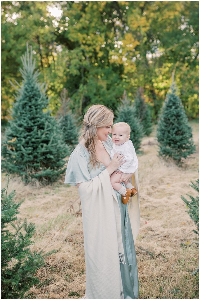 Mom snuggles baby during Christmas tree farm mini sessions at Butler's Orchard.