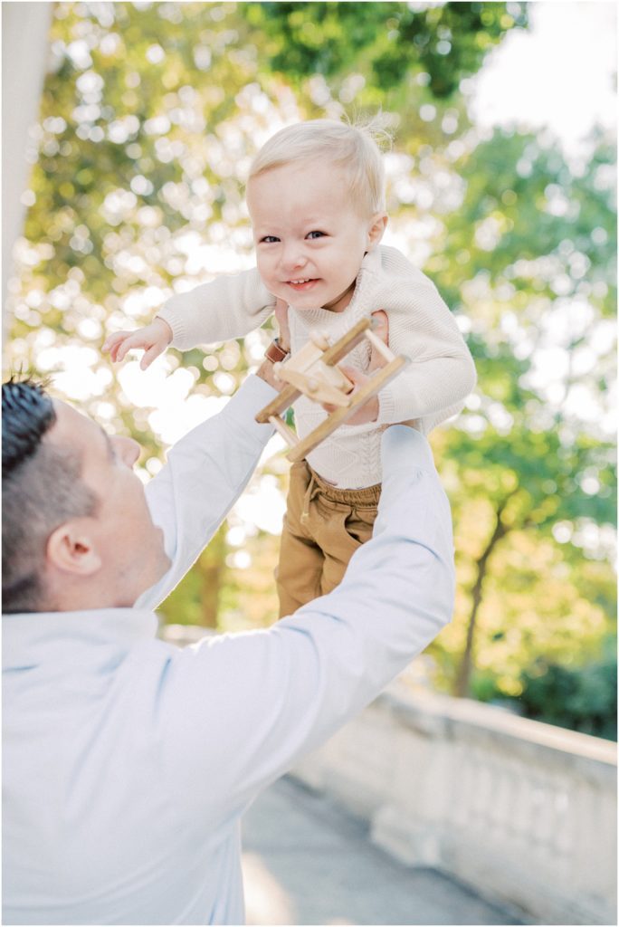 Little boy is thrown up in the air by his father during family photos.