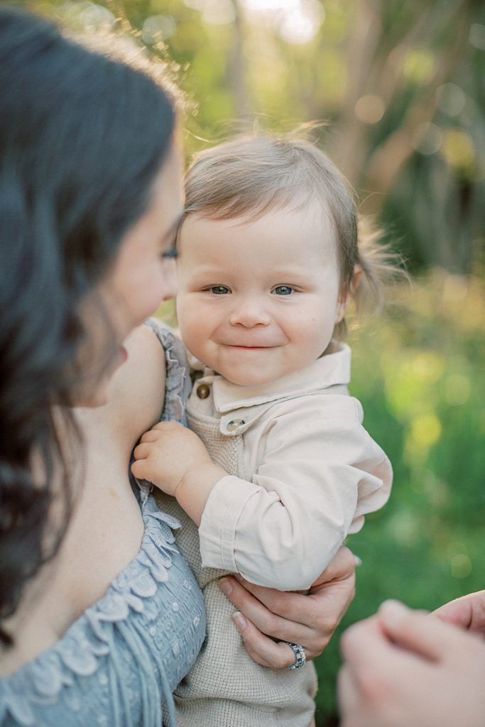 Toddler boy smiles while being held by his mother.