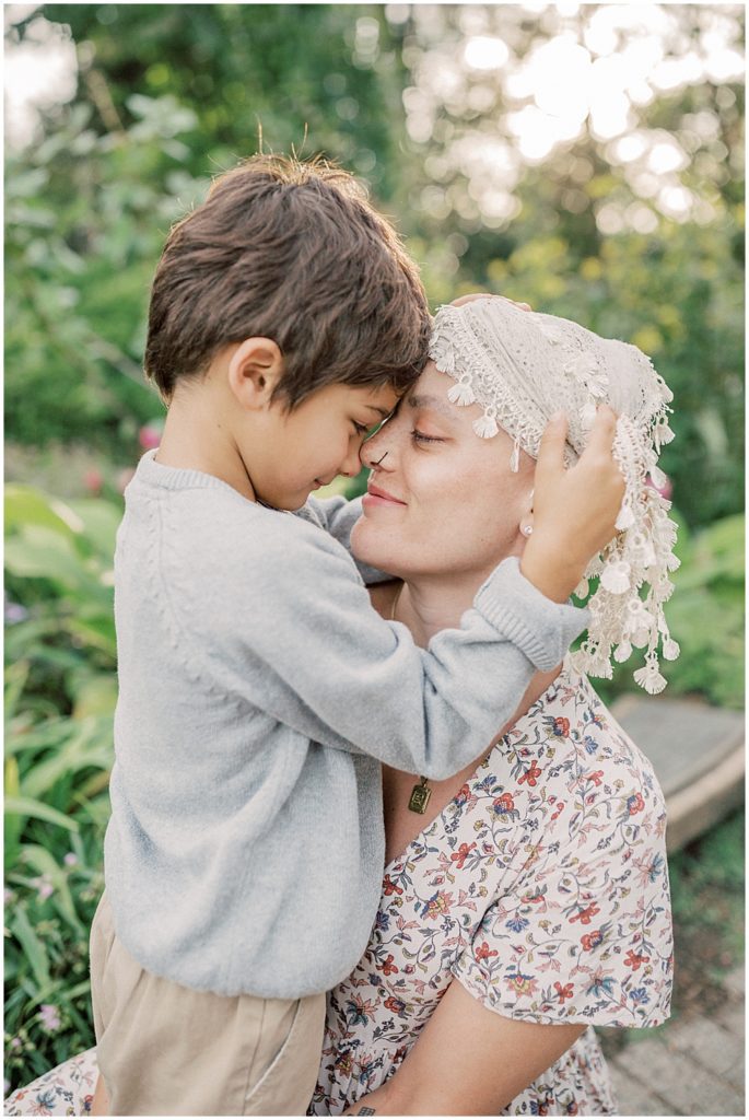 7-year-old boy wraps arms around his mother who kneels down next to him during extended family session at Green Springs Gardens in Northern Virginia. 