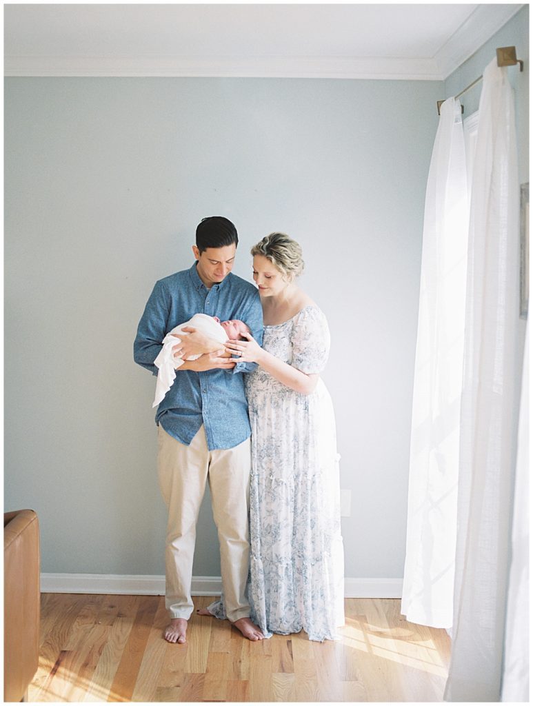 Mother and father stand in their home admiring their baby girl during Fairfax VA newborn session.