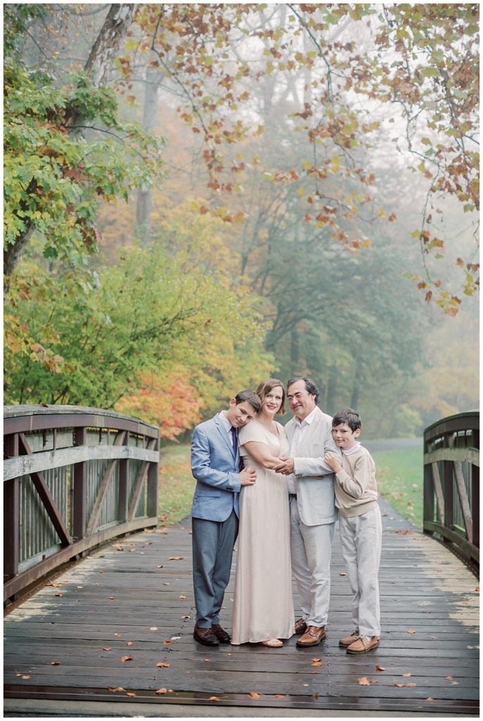 Mother, father, and their two older boys hug one another on a bridge at Brookside Gardens in Maryland.