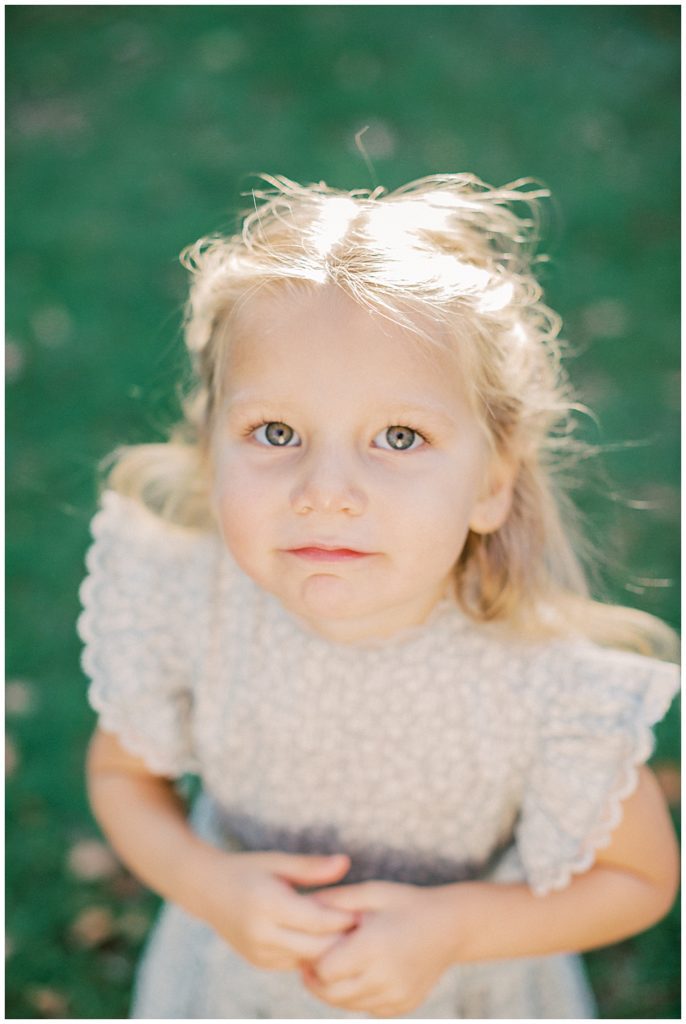 Little girl looks up at camera with green eyes.
