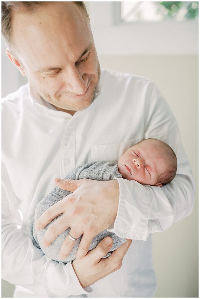 Newborn baby boy is held by his father.