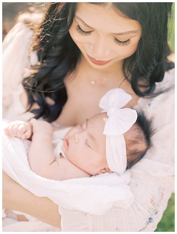 Close-up view of mother holding her baby girl wearing a large white bow.