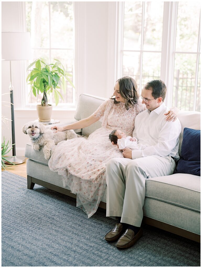 Mother and father sit on their couch with their newborn baby and dog in their Arlington home.