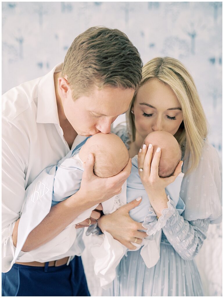 Blonde mother and father bring up their twin baby boys to give them a kiss during their Chevy Chase newborn session.
