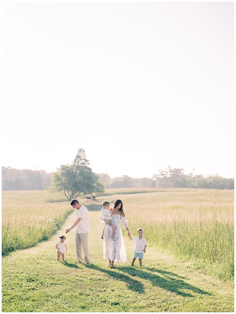 Mother and father walk with three young children through an open field during Manassas Battlefield family session.