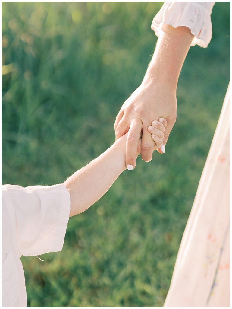 Close-up view of a little boy holding mother's hand.