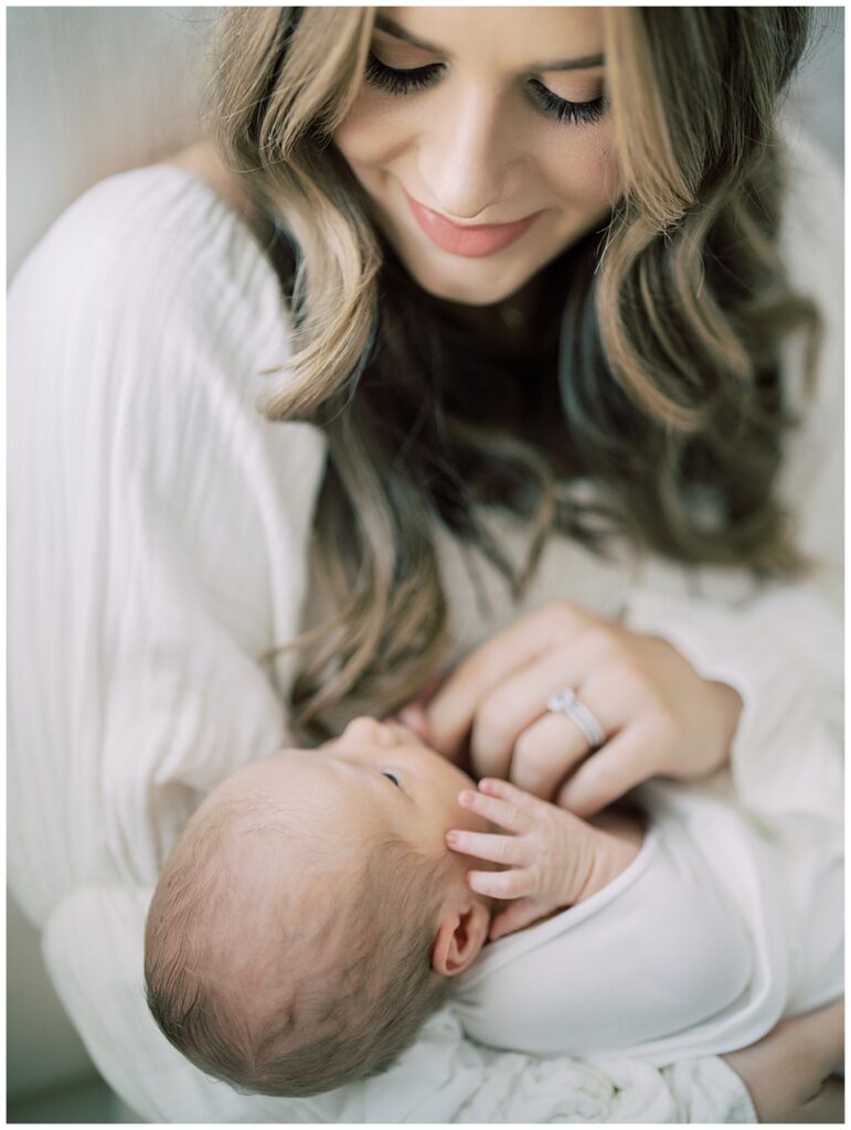 Mother with long brown hair places a finger on her baby girl during her North Bethesda newborn session.