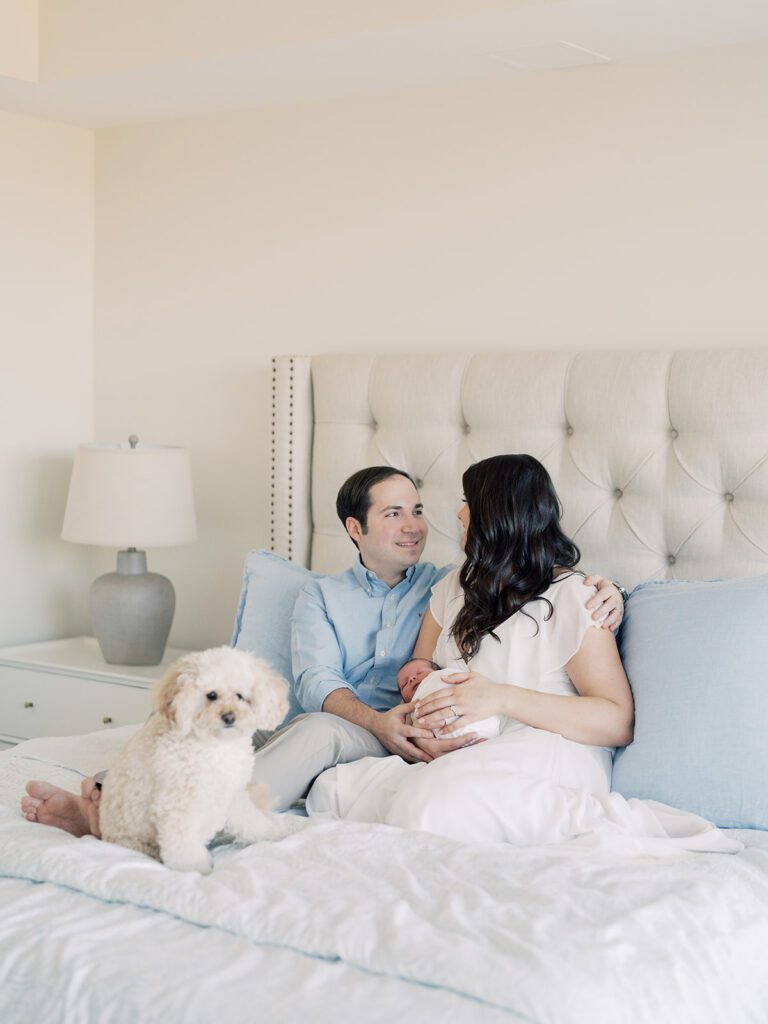 New parents sit on bed with their newborn and son during their Georgetown newborn session.