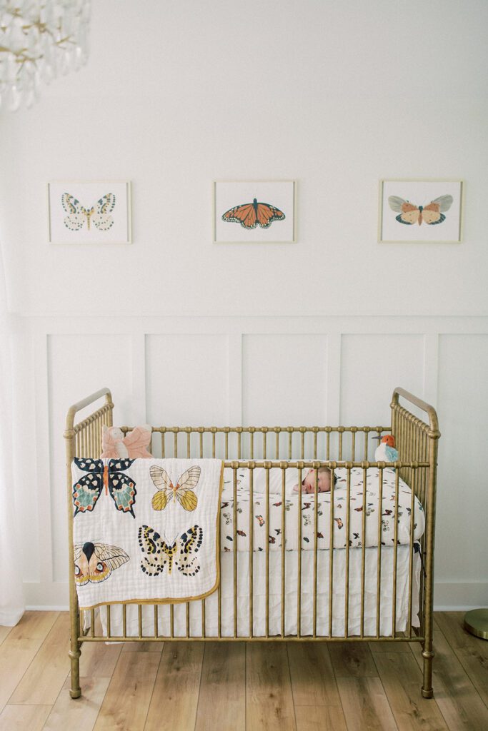 Baby lays in crib in butterfly-themed nursery.
