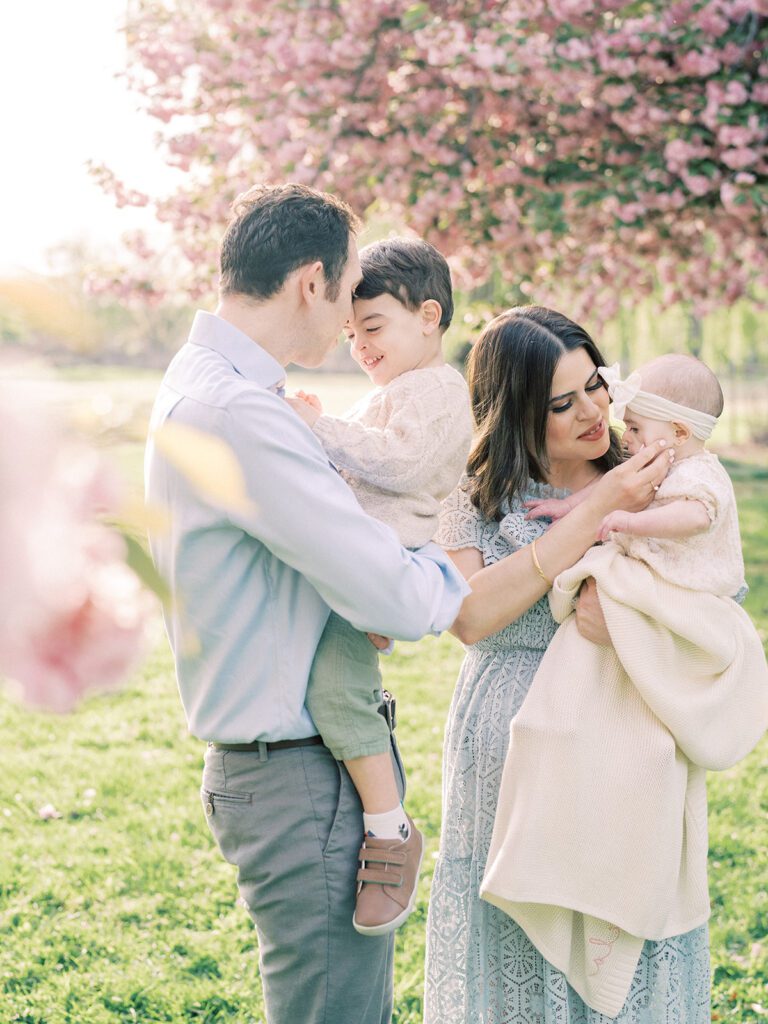 Parents hold their two children during the photo session at the Kwanzan cherry blossoms DC.