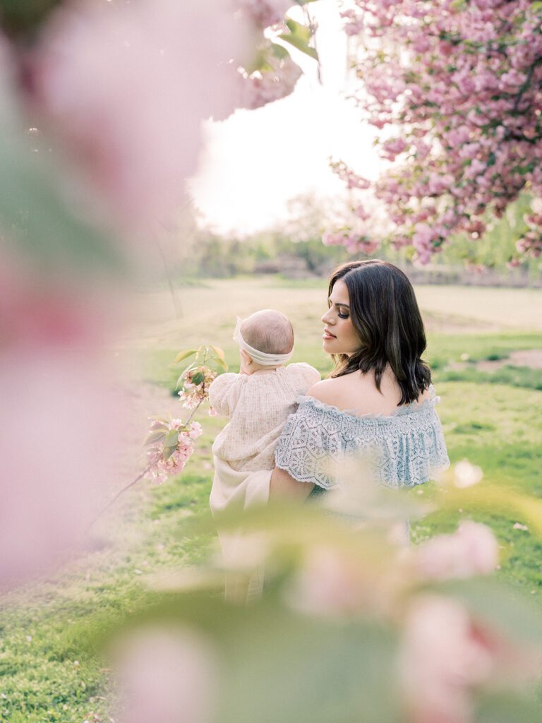 A mother with brown hair looks at her daughter amongst the Kwanzan cherry blossoms DC.