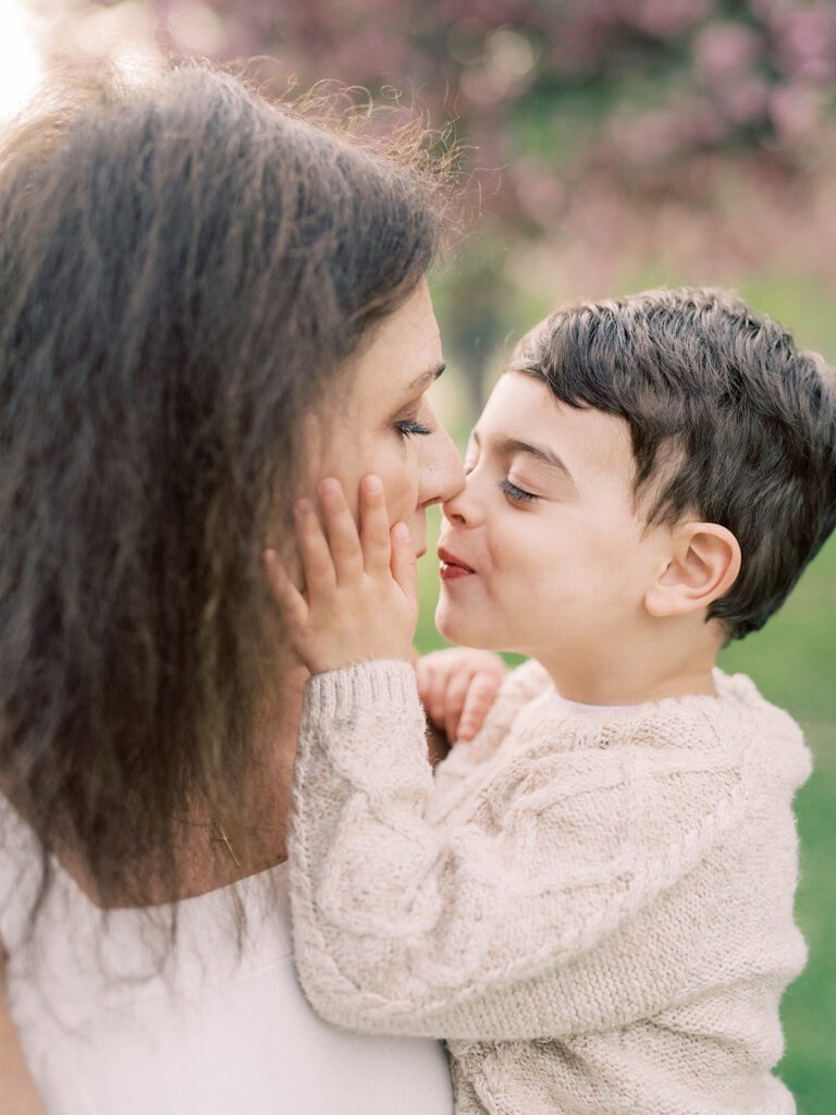 A little boy touches his nose to his grandmother's as he touches her face with his hand.